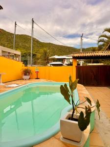 ein Swimmingpool mit einer Topfpflanze neben einem Haus in der Unterkunft Pousada Luz e Brilho Aluguel Temporada in Búzios