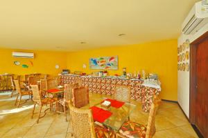 Un restaurante con paredes amarillas, mesas y sillas. en Pousada Doce Cabana, en Porto de Galinhas