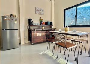 a kitchen with a table and a refrigerator at TUK&TOON House in Sathani Ban Thap Chang