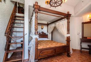 a bedroom with a wooden canopy bed and a staircase at Hotel Porto Perissa in Perissa
