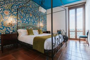 a bedroom with a bed with a blue and gold wall at Palazzo Giunta - Porta Marina Ortigia in Syracuse