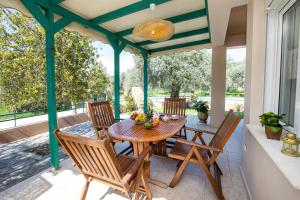a patio with a wooden table and chairs on a porch at Villa Aurum in Prinos