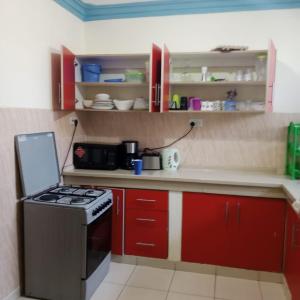 a kitchen with red cabinets and a stove top oven at Bamburi Mombasa two bedroom Cutraz homes apartments with swimming pool 005 in Mtwapa