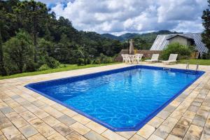 a swimming pool with blue water in a yard at Pousada Sonho Verde in Monte Verde