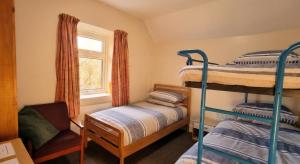 a bedroom with two bunk beds and a chair at Woodlands Centre in Betws-y-coed