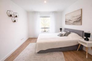 a white bedroom with a bed and a window at Heide-deluxe in Soltau