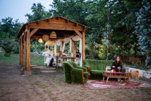 a woman sitting on a green couch under a pavilion at Bungalow TRADICIONS en FincaReal in Negreira