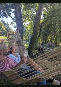 a man and woman sitting in a hammock with a glass of wine at Bungalow TRADICIONS en FincaReal in Negreira
