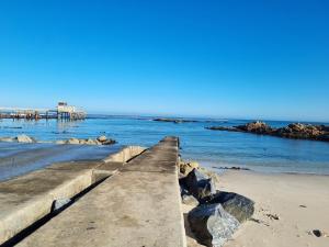 a walkway on a beach with a pier in the water at House Magriet in Doring Bay +5 photos