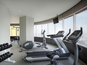 a gym with cardio equipment in a room with windows at Ibis Styles Jakarta Mangga Dua Square in Jakarta