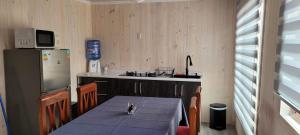 a small kitchen with a table and a refrigerator at Aegla lodge in Pichilemu