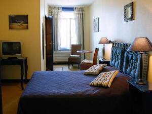 ein Schlafzimmer mit einem blauen Bett und einem Fernseher in der Unterkunft The Originals Boutique, Hôtel Angleterre, Fécamp in Fécamp