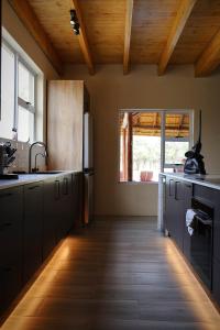 a kitchen with black cabinets and a wooden ceiling at Hemel Bushveld Lodge in Vaalwater