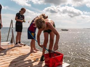 a young boy bending over a red box on a dock at DCU-Camping Grønninghoved Strand in Sjølund