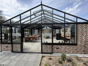 a glass house with a patio with tables and chairs at DCU-Camping Grønninghoved Strand in Sjølund +19 photos