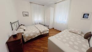 Zwei Betten in einem Zimmer mit weißen Wänden und Holzboden in der Unterkunft Ca' hygge in Lavagna