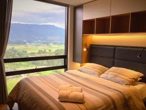a bedroom with a large bed with a large window at GV Aparta Suites - Centro Chía in Chía
