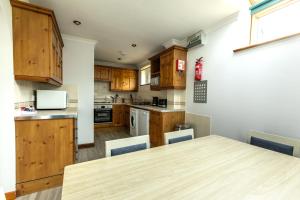 a kitchen with wooden cabinets and a wooden table at Tregurrian Villas in Newquay