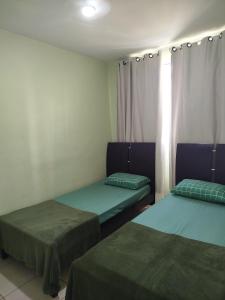 two beds sitting in a room with curtains at Apt 3Q Confort Aeroporto Confis Próx Cid Galo e Cid Admininstrativa Gov in Vespasiano