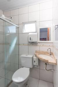 a white bathroom with a toilet and a sink at Pousada Brisa do Mar in Porto Seguro