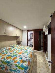 a bedroom with a bed with a colorful comforter at Hostal El Recreo in Barranquilla