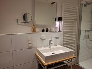 a white bathroom with a sink and a shower at Lachmöwe by DeJu -4 Sterne DTV-Klassifizierung- in Norderney +28 photos