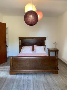 a bedroom with a wooden bed and a light fixture at Maison de l'Hermitage in Cucuron