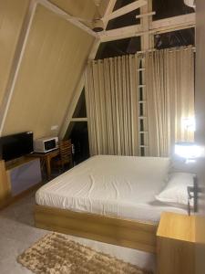 a bedroom with a bed and a desk with a computer at thesukoon in Bhīm Tāl