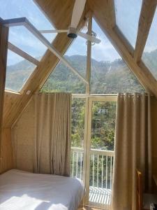 a bed in a room with a large window at thesukoon in Bhīm Tāl