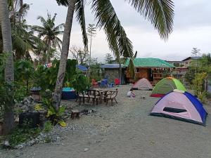 a camping area with tents and a table and chairs at Maybeth Haven Cabin in Baler
