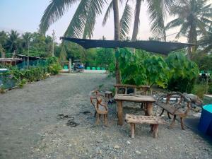 a group of chairs and a table with an umbrella at Maybeth Haven Cabin in Baler