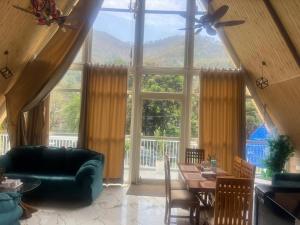 a living room with a couch and a table and a large window at thesukoon in Bhīm Tāl