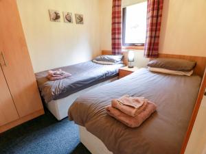 two beds in a bedroom with towels on them at Thistle Lodge in Dunoon
