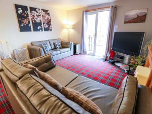 a living room with a couch and a television at Thistle Lodge in Dunoon