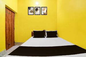 a yellow room with a bed with three pictures on the wall at Capital O Sri Krishna Palace Near Sum Hospital in Durgāpur
