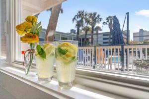 two glasses sitting on a window sill with flowers at Sun Fun in Myrtle Beach