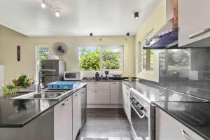 a large kitchen with white cabinets and a sink at Modern Villa with Pool & Garden in Farehau