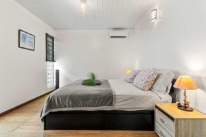 a white bedroom with a bed and a night stand at Modern Villa with Pool & Garden in Farehau