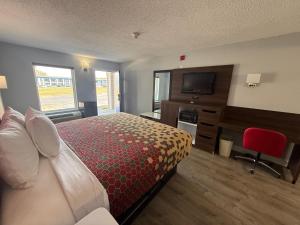 a hotel room with a bed and a flat screen tv at Econo Lodge Ruther Glen in Ruther Glen