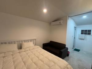 a bedroom with a bed and a black chair at Baan Kru Ju Single Room in Phuket