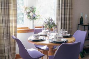 a dining room table with purple chairs and a table with wine glasses at The Nest - Chandlers in Rothesay