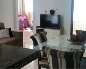 a living room with a glass table and a television at Aluguel de quarto com suite in Aracaju