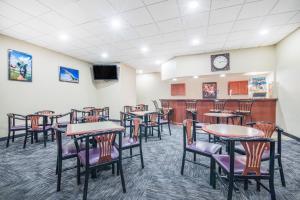 une salle à manger avec des tables, des chaises et une télévision dans l'établissement Howard Johnson by Wyndham Rapid City, à Rapid City