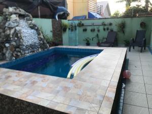 a swimming pool in a backyard with a waterfall at Casa com piscina em Peruíbe in Peruíbe