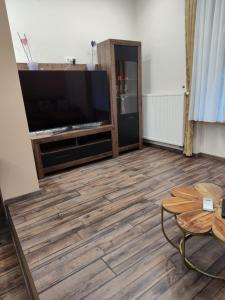 a living room with a flat screen tv and a wooden floor at Robert's Apartment in Celje