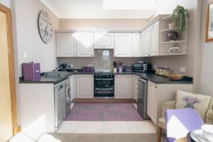 a kitchen with white cabinets and black counter tops at The Nest - Chandlers in Rothesay +9 photos