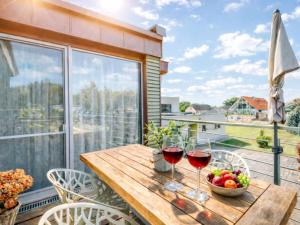 a wooden table with two glasses of wine on a balcony at Schäfers - Ihr Wohlfühlort, Ferienwohnungen & Ferienhaus am Naturteich an 2 Seen bei Leipzig in Großpösna