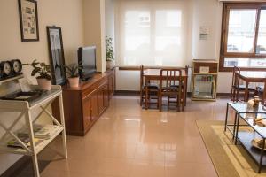 a living room with a tv and a table and chairs at Hotel Playa Poniente in Gijón