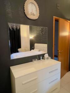 a bathroom with a white dresser and a mirror at private room in a shared apartment in Seveso