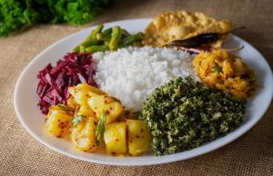 a plate of food with rice and vegetables on a table at Colombo Residency -Pent House in Kotuwegoda